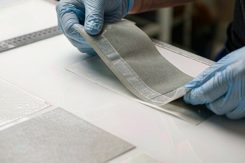 Technician peeling adhesive tape from a matte release film sample in a quality lab